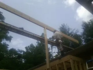 Carpenter setting a ridge beam over a new addition frame — Ice Dam Removal by Roofing Brothers in Oldsmar