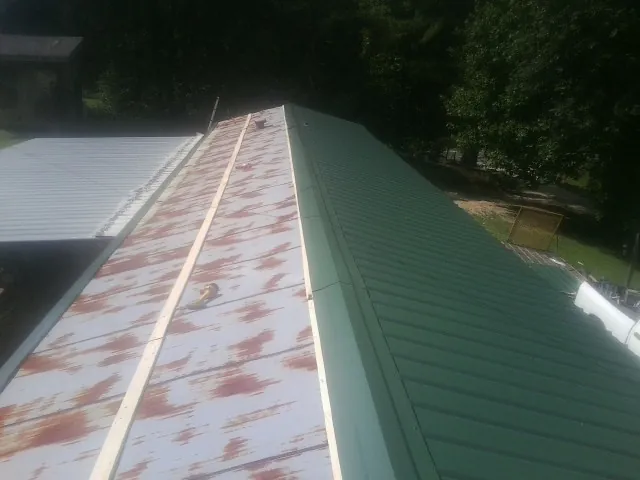 Old rusted panels beside newly installed green metal roofing — Wind Damage Roof Repair by Roofing Brothers in Oldsmar