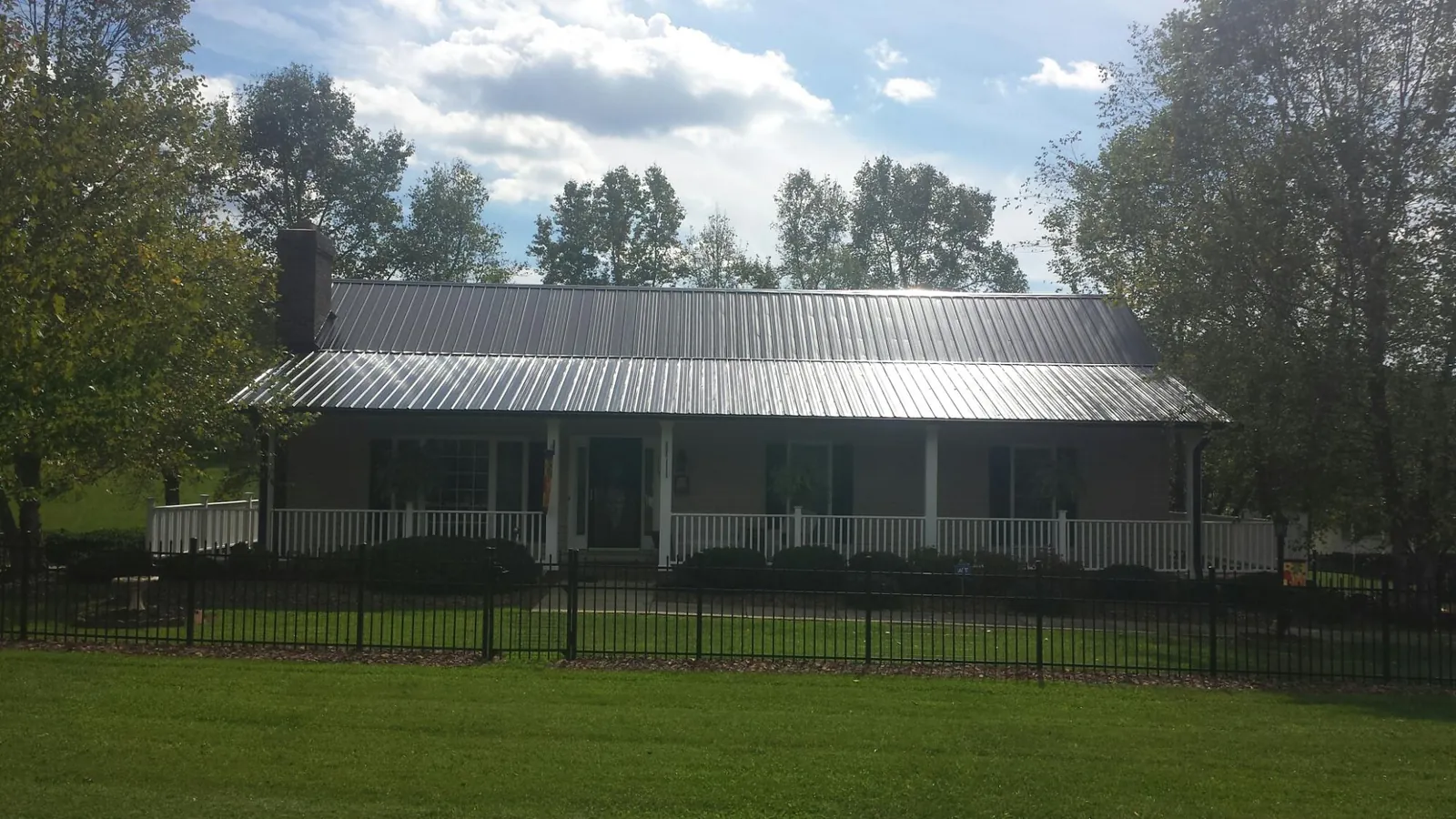 Gray metal roof on a brick ranch with a full width front porch — Gutter Guard Installation work by our crew in Oldsmar